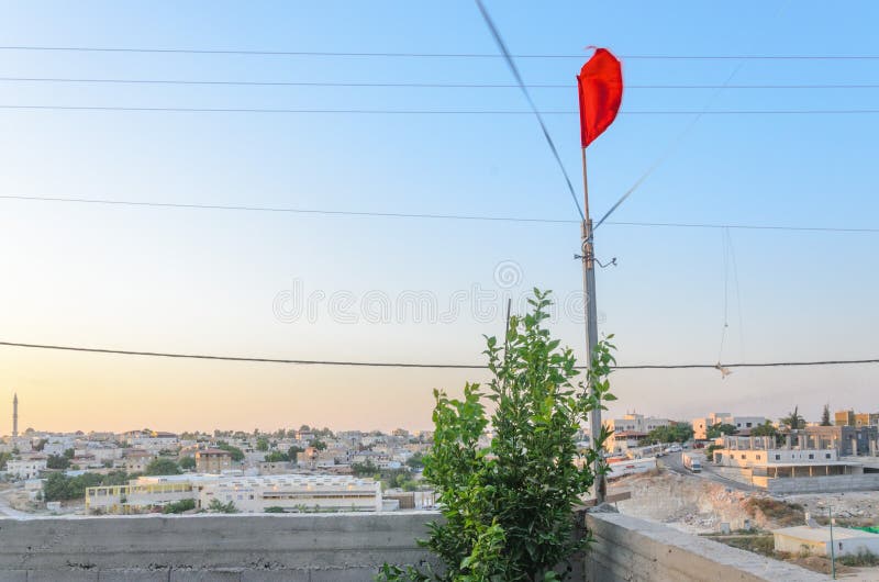 Escarlate da bandeira e árvore verde no por do sol sobre a cidade de Rahat, perto de Beersheba, o Negev, Israel imagens de stock royalty free Escarlate da bandeira e árvore verde no por do sol sobre a cidade de Rahat, perto de Beersheba, o Negev, Israel imagens de stock royalty free