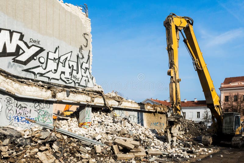 Escavador demolindo prédio antigo que muralha com grafite no dia imagem de stock royalty free