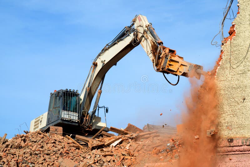 Escavador demolindo um edifício de tijolos Edifício de demolição de máquinas imagem de stock