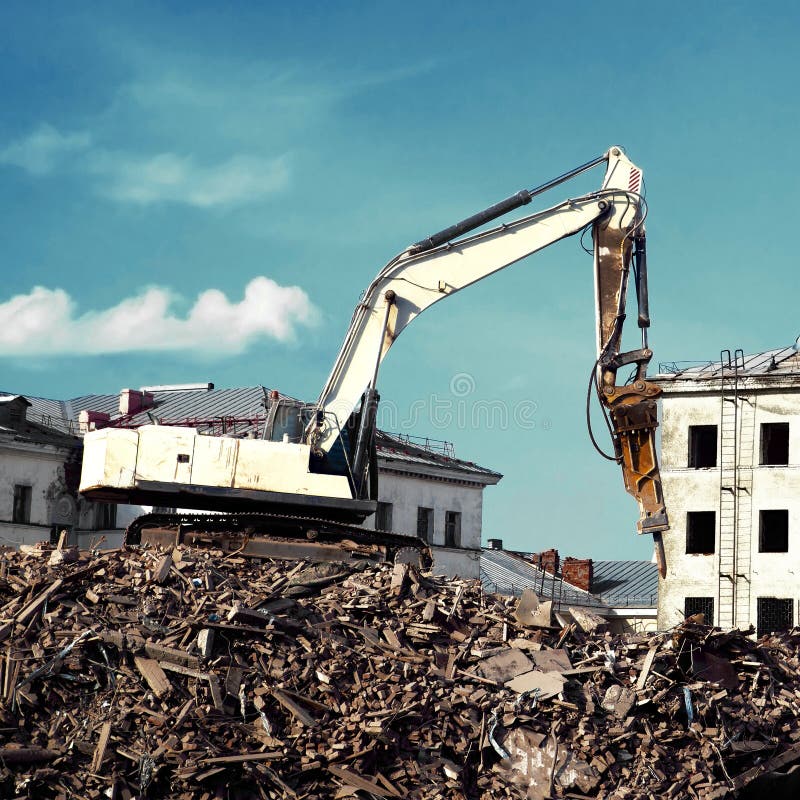 Escavador demolindo um edifício de tijolos Edifício de demolição de máquinas
