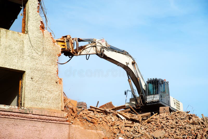 Escavador demolindo um edifício de tijolos. edifício de demolição de máquinas imagens de stock