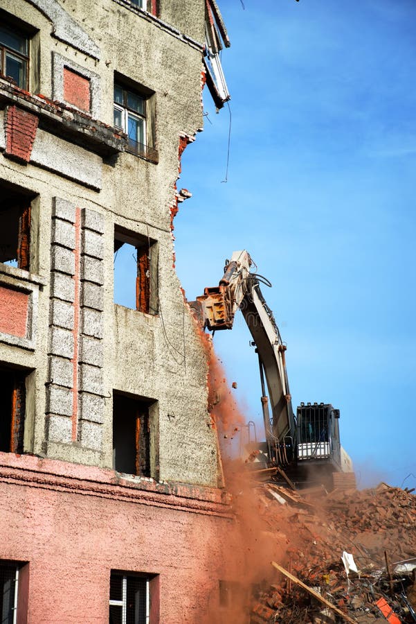 Escavador demolindo um edifício de tijolos. edifício de demolição de máquinas imagens de stock royalty free