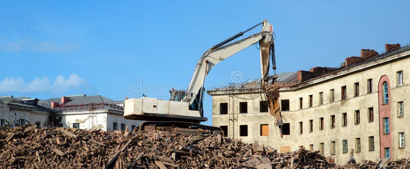 Escavador demolindo um edifício de tijolos. edifício de demolição de máquinas imagem de stock