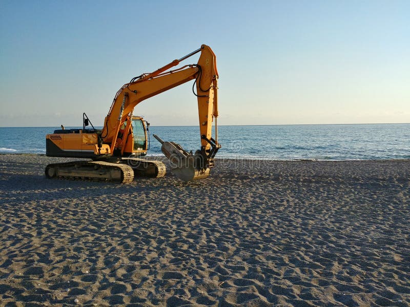 Escavadora amarela está numa praia foto de stock royalty free