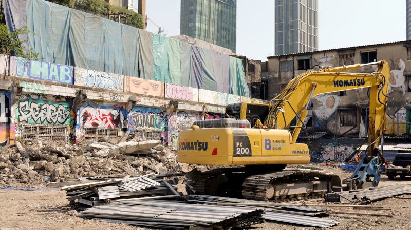Escavadora amarela grande junto a paredes cobertas de graffiti foto de stock