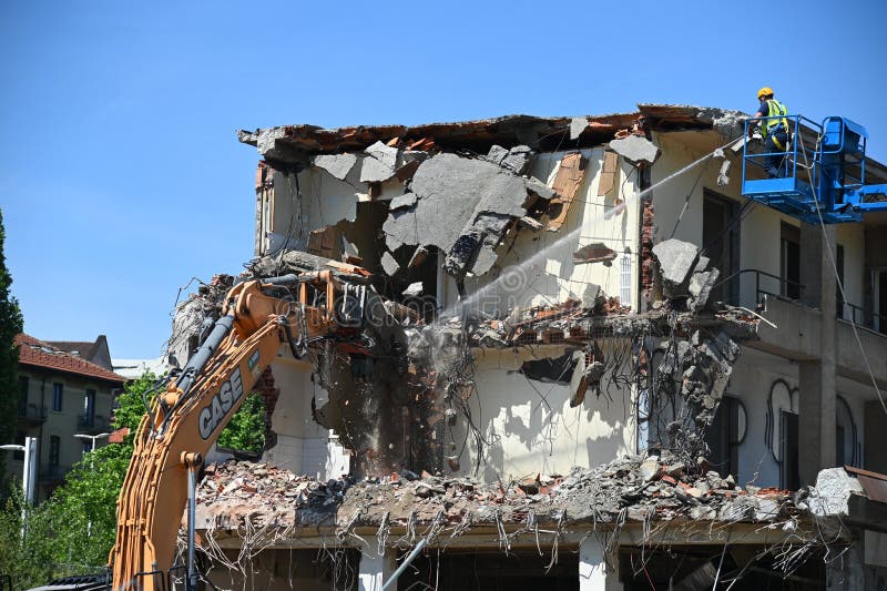 Escavadora demolindo prédio abandonado no local escolhido para novo desenvolvimento urbano imagens de stock