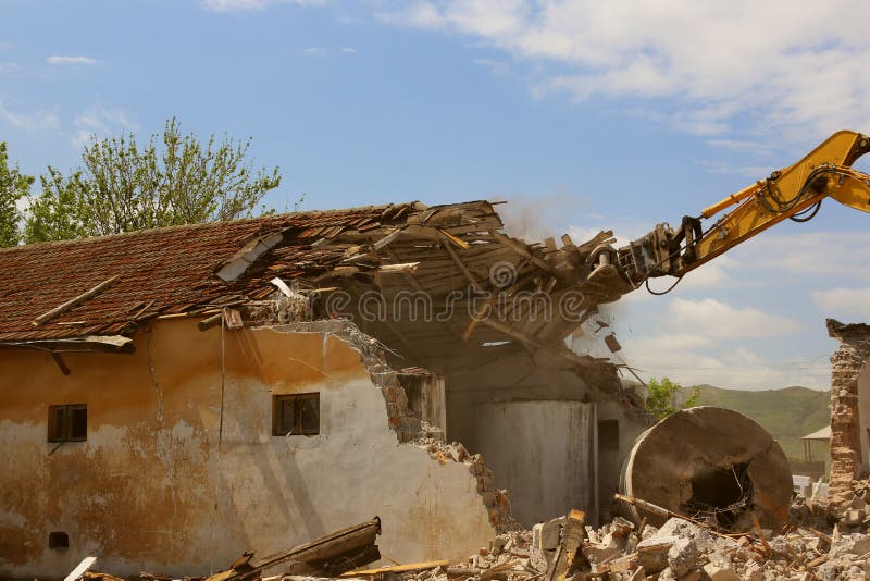 Escavadora rastreada demolindo prédios antigos foto de stock