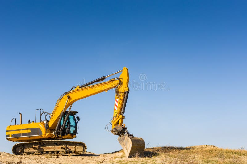 Escavatore giallo sotto un chiaro cielo blu fotografia stock libera da diritti Escavatore giallo sotto un chiaro cielo blu fotografia stock libera da diritti