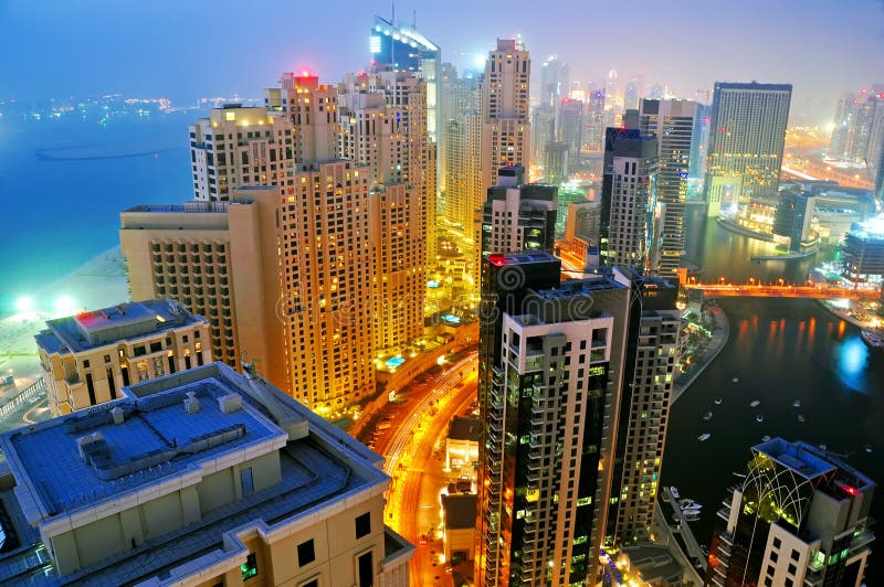 A high level view of a night scene of Jumeirah Beach Residence and Dubai Marina with the Palm in the background. A high level view of a night scene of Jumeirah Beach Residence and Dubai Marina with the Palm in the background