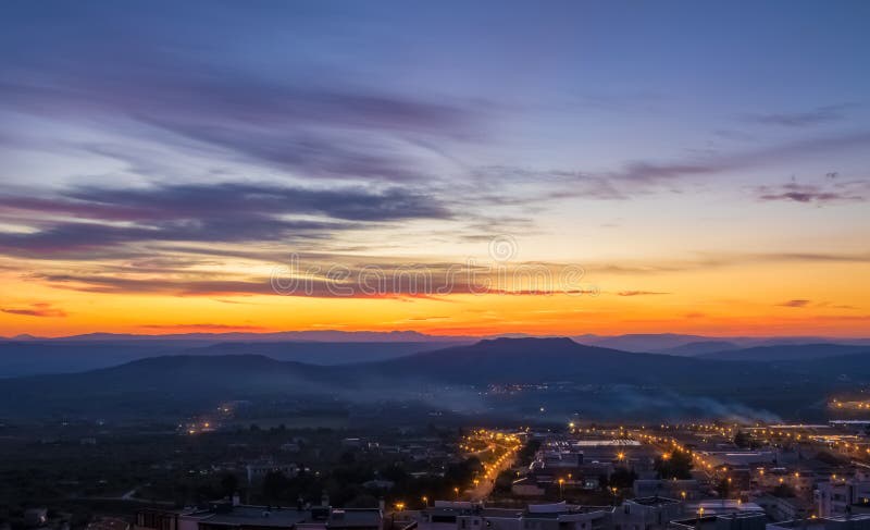Escena de la puesta del sol con las montañas en fondo y la ciudad Matera en el primero plano, visión industrial fotos de archivo libres de regalías Escena de la puesta del sol con las montañas en fondo y la ciudad Matera en el primero plano, visión industrial fotos de archivo libres de regalías