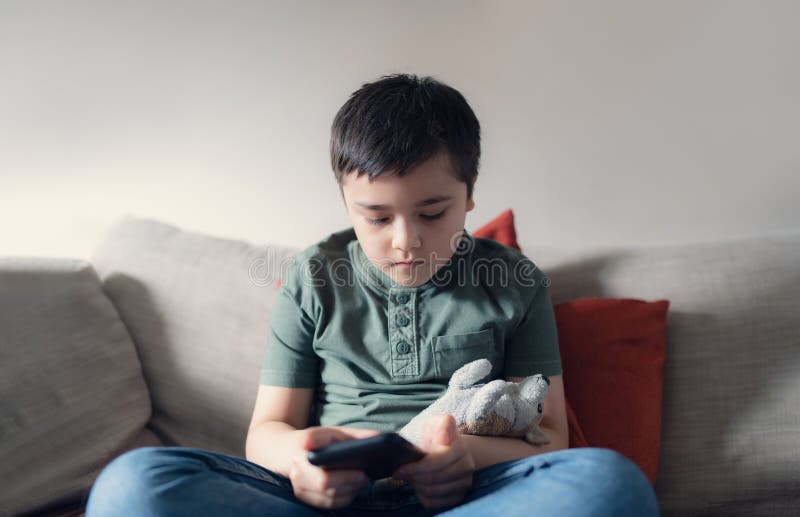 retrato menino jogando no celular enquanto espera por comida, garoto  sentado na cafeteria enviando texto para amigos, criança jogando jogo online  no celular. crianças com conceito de tecnologia 11248716 Foto de stock