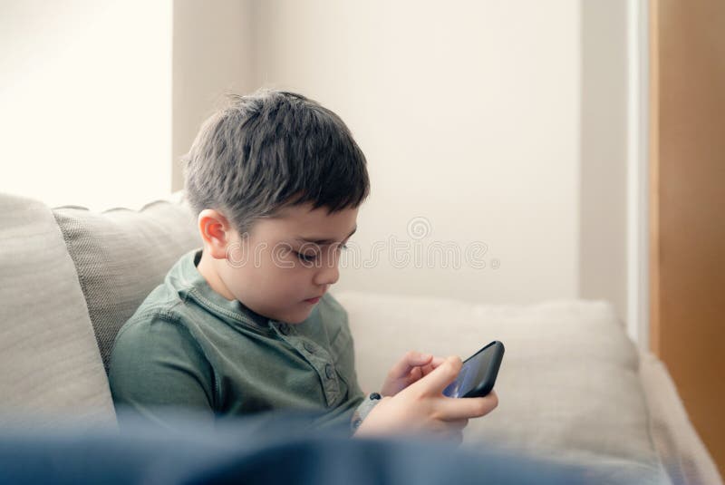 retrato menino jogando no celular enquanto espera por comida, garoto  sentado na cafeteria enviando texto para amigos, criança jogando jogo online  no celular. crianças com conceito de tecnologia 11248716 Foto de stock