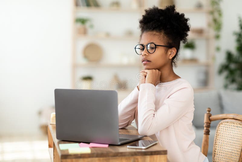 Escolar africana en una laptop con una lección en línea en casa imagenes de archivo