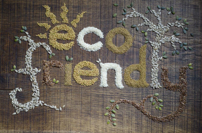 The phrase 'Eco Friendly', decoratively written and in sesame seeds, sunflower seeds, flax seeds, alfafa seeds, fenugreek seeds and pumpkin seeds, on a dark wooden surface. The phrase 'Eco Friendly', decoratively written and in sesame seeds, sunflower seeds, flax seeds, alfafa seeds, fenugreek seeds and pumpkin seeds, on a dark wooden surface.