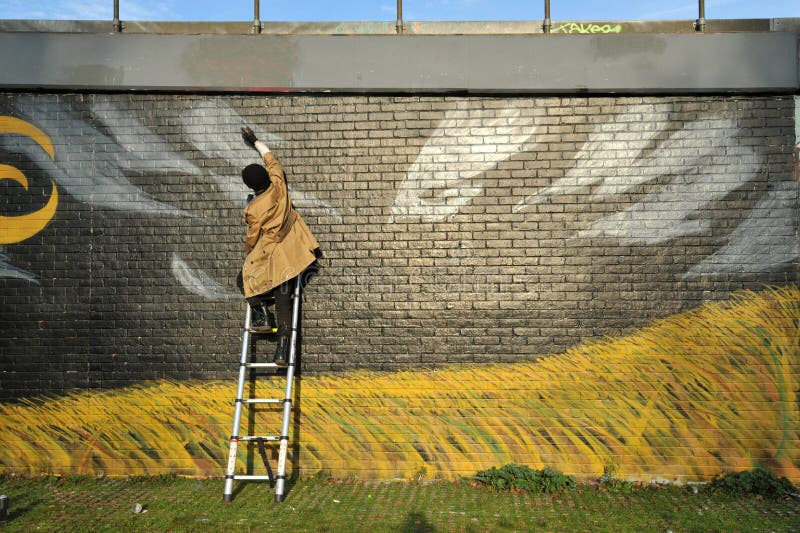 Escritor de graffitis trabajando en las calles del Este de Londres, Inglaterra foto de archivo Escritor de graffitis trabajando en las calles del Este de Londres, Inglaterra foto de archivo