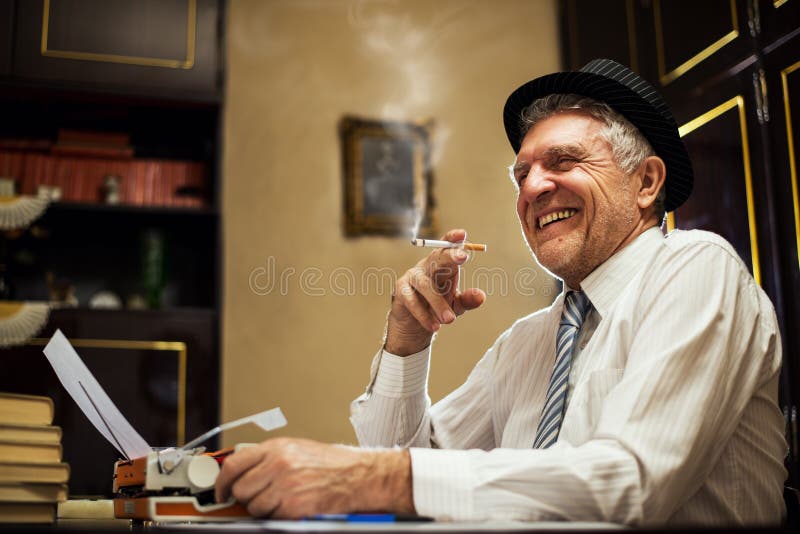 Escritor retro do homem superior com um cigarro foto de stock Escritor retro do homem superior com um cigarro foto de stock