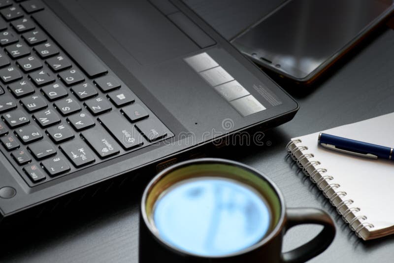 Escritorio con el ordenador portátil, el teléfono elegante, los cuadernos, las plumas, las lentes y una taza de té Opinión de áng foto de archivo Escritorio con el ordenador portátil, el teléfono elegante, los cuadernos, las plumas, las lentes y una taza de té Opinión de áng foto de archivo