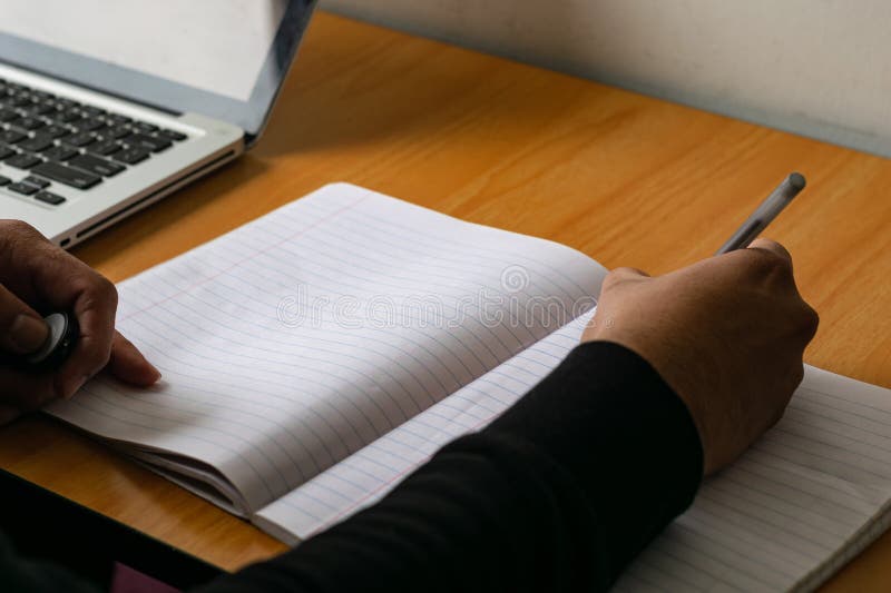 Male hand writing with pen on a lined notebook. Male hand writing with pen on a lined notebook