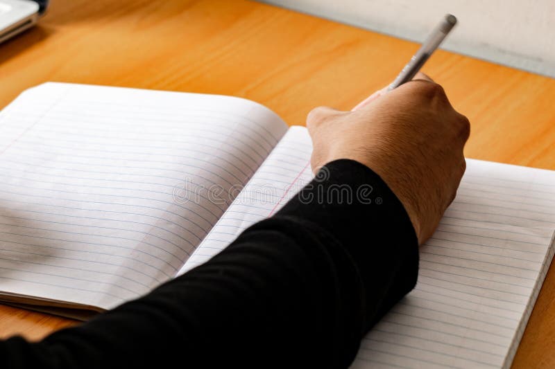 Male hand writing with pen on a lined notebook. Male hand writing with pen on a lined notebook