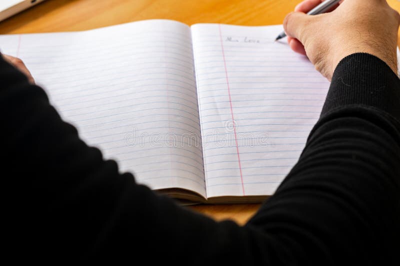 Male hand writing with pen on a lined notebook. Male hand writing with pen on a lined notebook