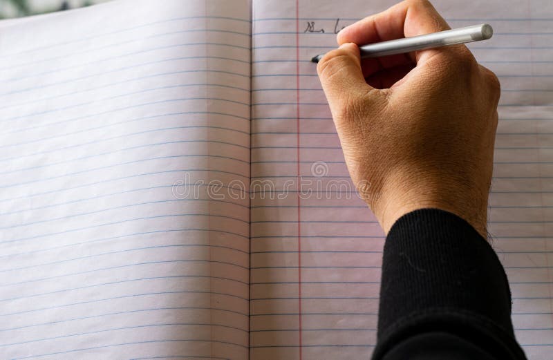 Male hand writing with pen on a lined notebook. Male hand writing with pen on a lined notebook