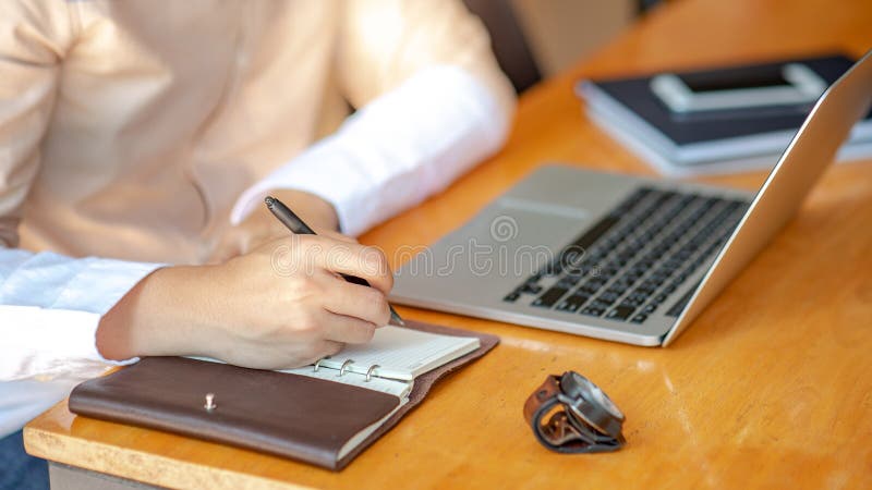 Escritura masculina de la mano en el cuaderno en el escritorio fotografía de archivo Escritura masculina de la mano en el cuaderno en el escritorio fotografía de archivo