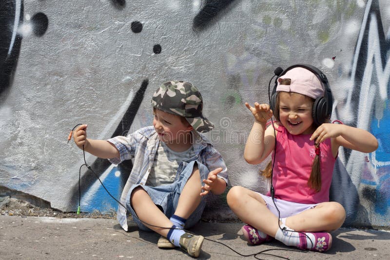 Kids listen to music abstract concept against graffiti wall in the city. Kids listen to music abstract concept against graffiti wall in the city