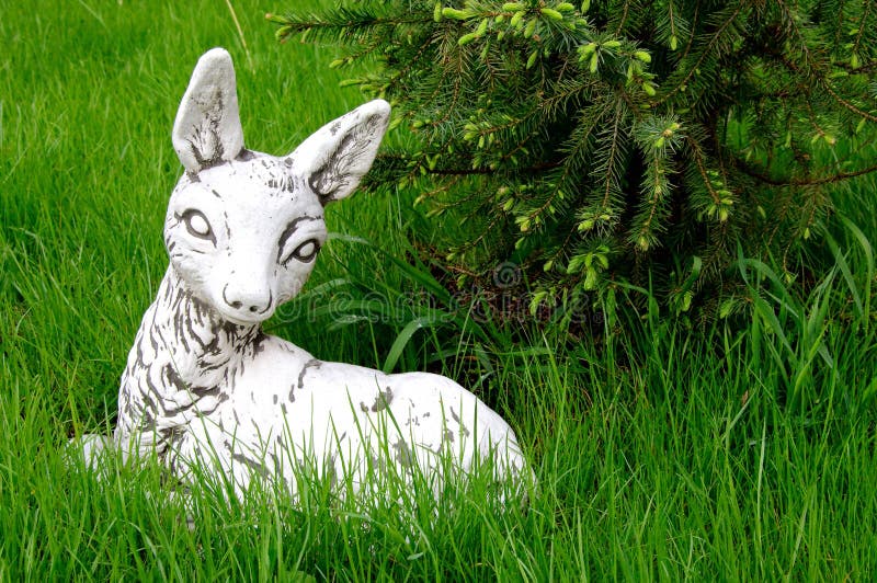 Escultura branca do bambi dos cervos da pedra que encontra-se no gramado verde fotografia de stock royalty free Escultura branca do bambi dos cervos da pedra que encontra-se no gramado verde fotografia de stock royalty free