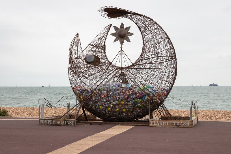 Escultura de peixe numa praia cheia de garrafas plásticas para encorajar a reciclagem e