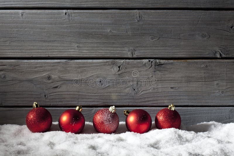 Esferas rojas de la Navidad en la pila de nieve contra la pared de madera fotografía de archivo libre de regalías Esferas rojas de la Navidad en la pila de nieve contra la pared de madera fotografía de archivo libre de regalías