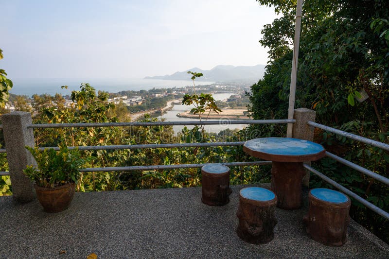 Espace d'observation à la Pagode Kao Hua Jook avec des sièges en rondins rustiques et un haut-parleur donnant sur le lac Chaweng e. Zone d'observation de la Pagode Kao Hua Jook avec des sièges en rondins rustiques et un haut-parleur donnant sur le lac Chaweng et le littoral montagneux de Ko Samuis à travers la végétation tropicale