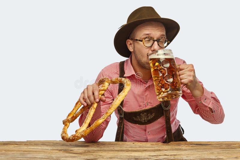 Portrait of delightful bearded man in hat and traditional Bavarian costume with glass of frothy beer isolated over white background. Oktoberfest, traditions, drinks and food concept. Copy space for ad. Portrait of delightful bearded man in hat and traditional Bavarian costume with glass of frothy beer isolated over white background. Oktoberfest, traditions, drinks and food concept. Copy space for ad