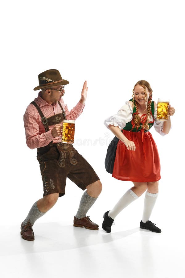 Full lenght portrait of emotional man and woman wearing folk festival outfits, having glasses with Bavarian beer. Concept of alcohol, traditions, holidays, festival. Copy space for ad. Full lenght portrait of emotional man and woman wearing folk festival outfits, having glasses with Bavarian beer. Concept of alcohol, traditions, holidays, festival. Copy space for ad