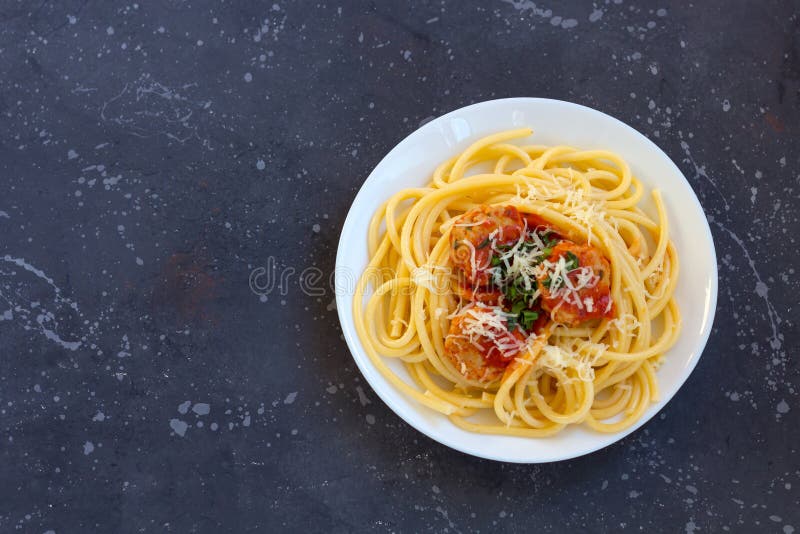 Espaguetes com almôndegas, molho de tomate e queijo parmesão na placa branca no fundo escuro foto de stock royalty free Espaguetes com almôndegas, molho de tomate e queijo parmesão na placa branca no fundo escuro foto de stock royalty free
