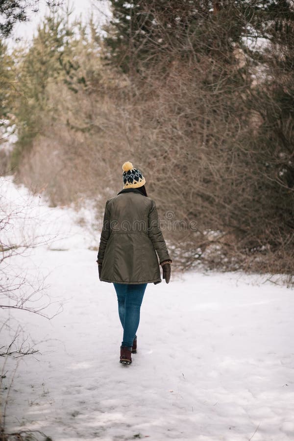 Mujer caminando por el camino en el parque en invierno. Relajación en la  naturaleza de la nieve. Mujer con ropa de abrigo, gorro de punto con pompón  y abrigo de piel Fotografía