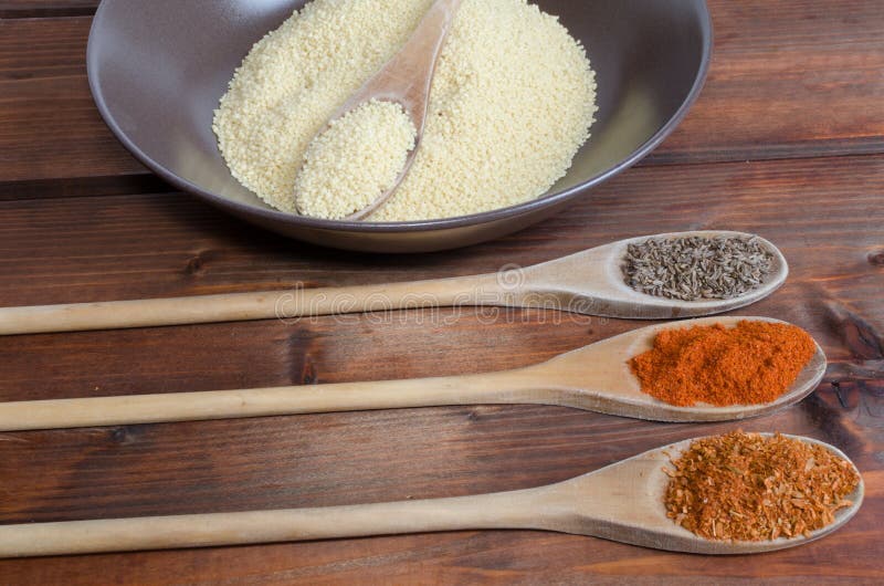 Especiarias numa colher com uma tigela de cuscuz foto de stock royalty free
