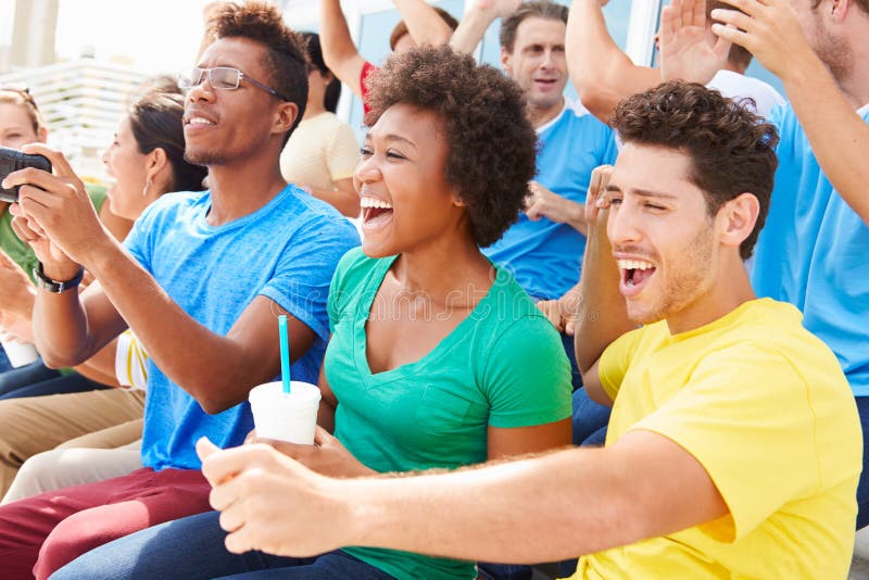Spectators In Team Colors Watching Sports Event Smiling. Spectators In Team Colors Watching Sports Event Smiling