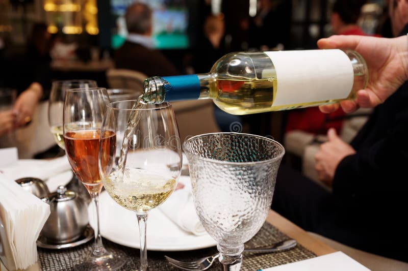 Waiting is pouring white wine in restaurant. Waiting is pouring white wine in restaurant