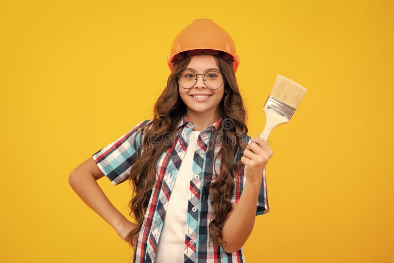 Esperto di piccoli costruttori di casco nel cantiere. Pittore di ragazza con spazzolatrice o rullo per verniciatura. Bambino immagini stock libere da diritti