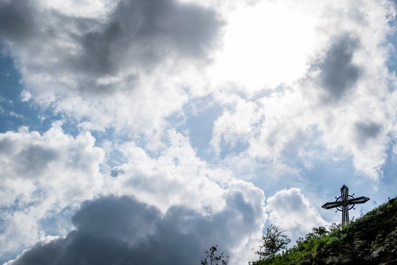 Esponga al sole dietro le nuvole e l'incrocio cristiano fotografia stock Esponga al sole dietro le nuvole e l'incrocio cristiano fotografia stock
