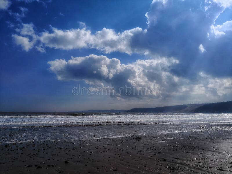 Esponga al sole i raggi che scoppiano attraverso le nuvole sulla spiaggia di Scarborough fotografia stock Esponga al sole i raggi che scoppiano attraverso le nuvole sulla spiaggia di Scarborough fotografia stock