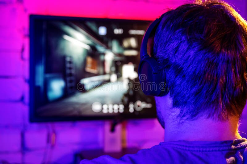 Happy professional player streaming esport tournament using microphone and  headphones, enjoying a multiplayer game. Competitive gamer playing online  video game at home. Neon color. Cyber sport concept Stock Photo