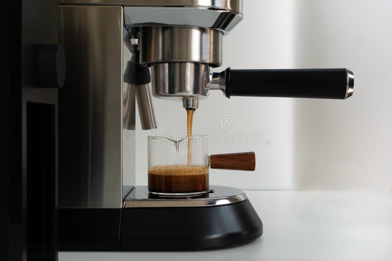 The Espresso Coffee Flowing from Coffee Machine into a Small Glass