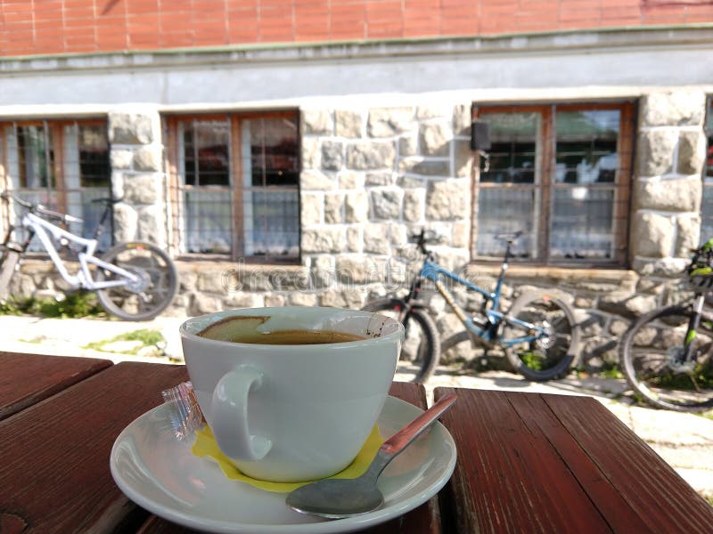 Espresso káva na stole s bicyklami na pozadí pri chate.