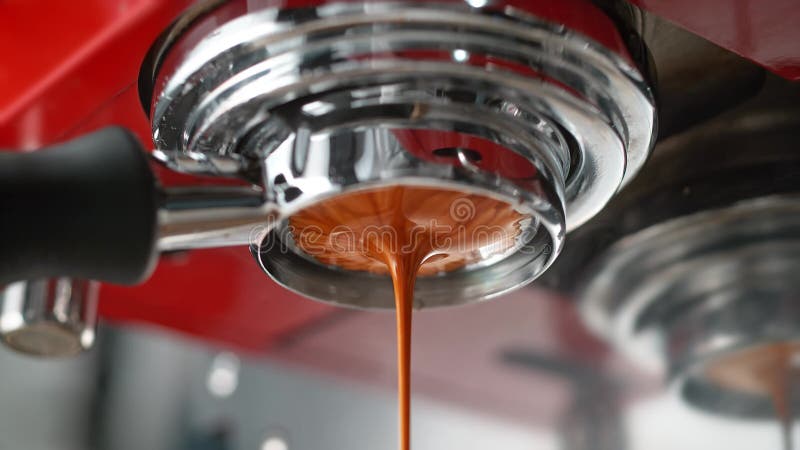 Espresso estratto da portafiltro senza fondo in un produttore di caffè rosso in slow motion