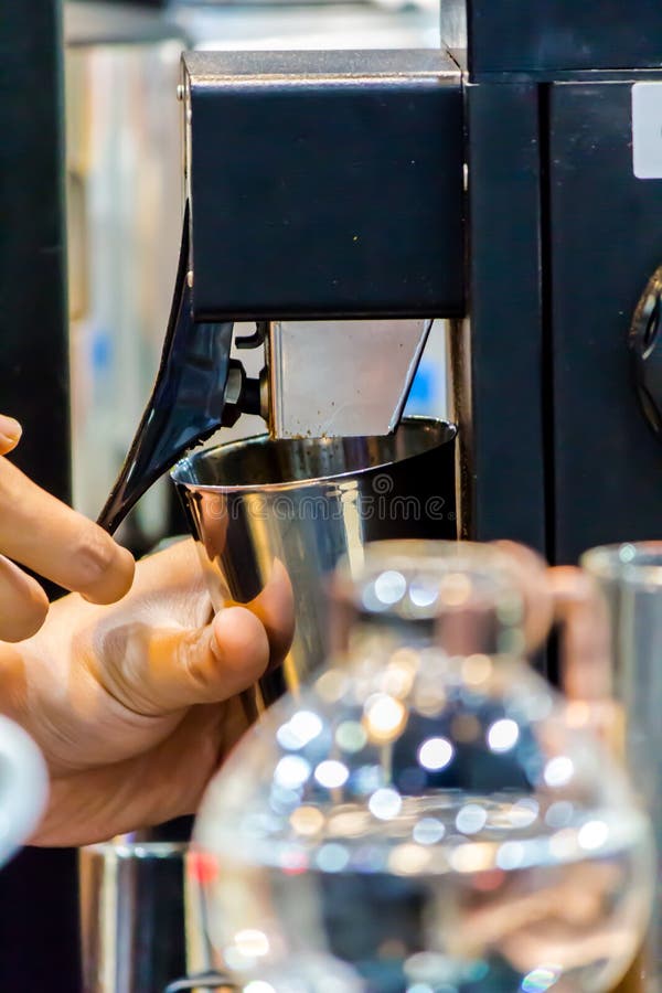 Espresso Machine Grinding Roasted Coffee Bean into Cup Stock Photo