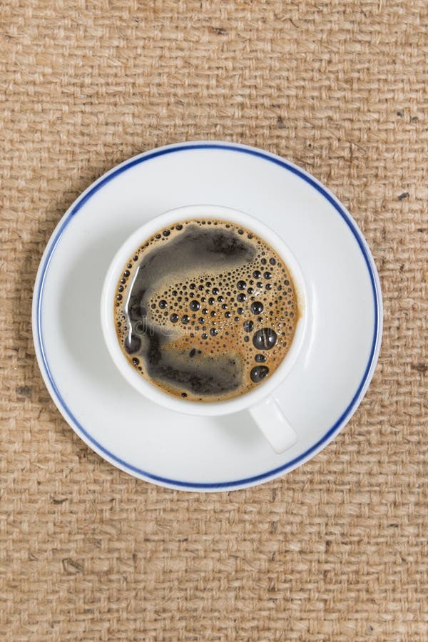 Espressokaffe i vit kuper. Bästa sikt av espressokaffe över en hessianstygbakgrund