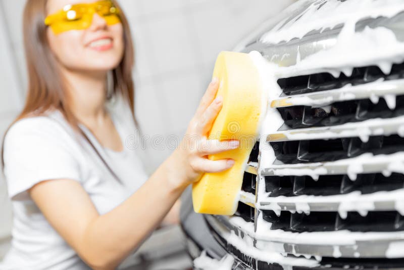 Hand woman car wash foam with yellow sponge headlights. Hand woman car wash foam with yellow sponge headlights.