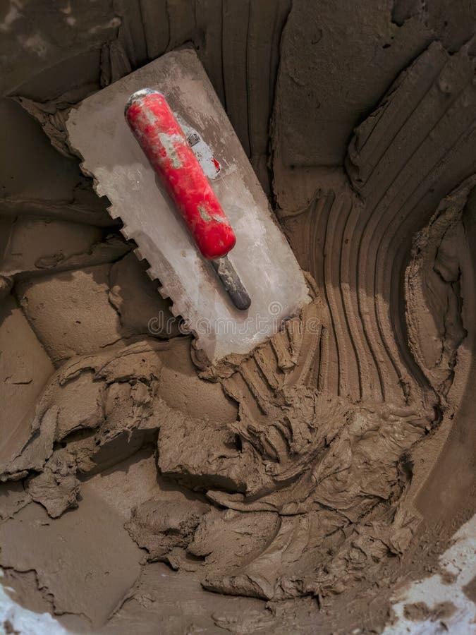 Spatula and mix for laying ceramic tiles. Laying tiles at a construction site. Selective focus, plenty of copy space. Spatula and mix for laying ceramic tiles. Laying tiles at a construction site. Selective focus, plenty of copy space