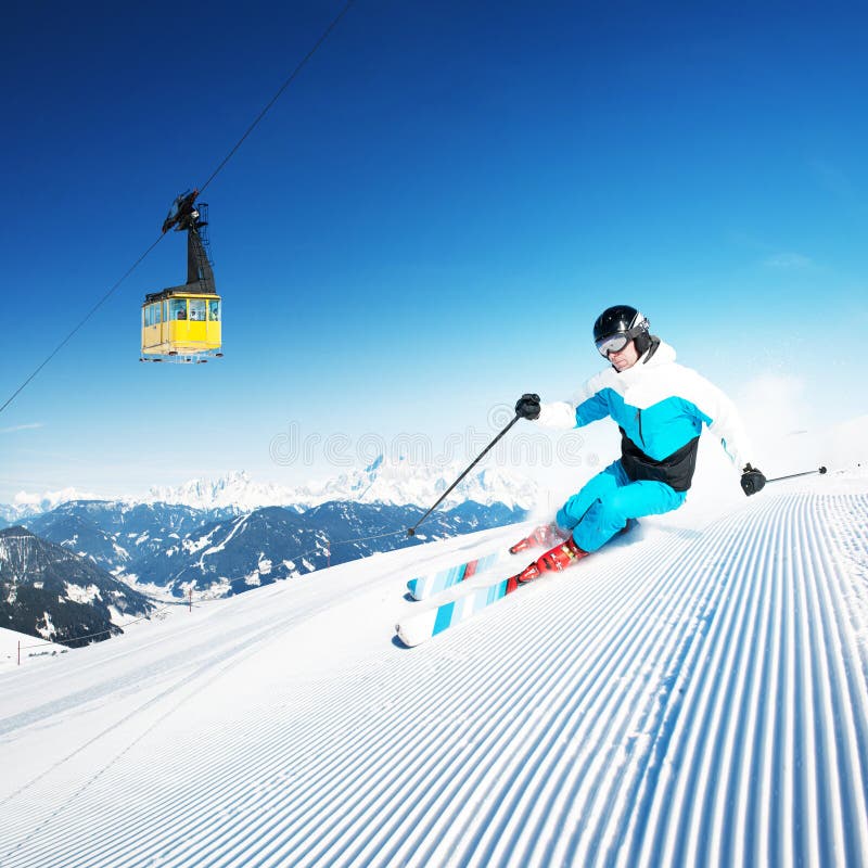 Esquiador en montañas, piste preparado y día asoleado